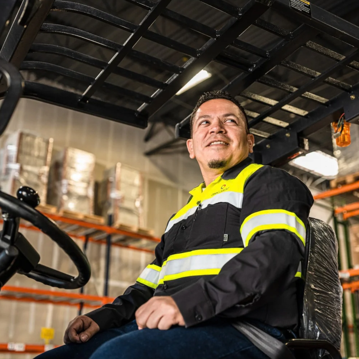 Man on forklift working in warehouse in high vis workwear