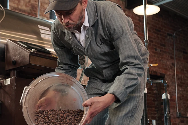 Industrial Uniform Rentals - Man in coveralls working on factory with bucket of coffee beans